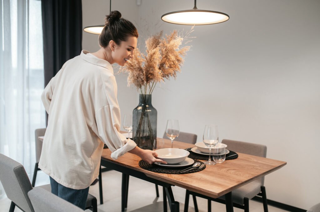 Young woman in a swhite shirt putting plates on the table