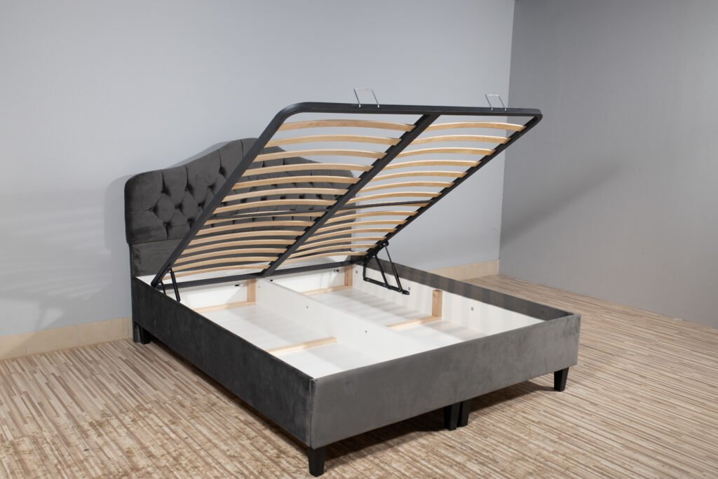 Bed with gray upholstery, without mattress and with opened storage in an empty room