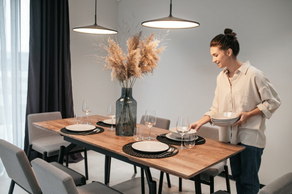 Young dark-haired woman serving the table in the kitchen De Beste Uitschuifbare Tafels voor Studio’s & Tiny Houses / gedekt